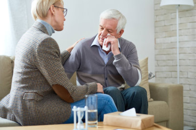 portrait of female psychiatrist comforting senior men crying during therapy session