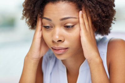 people, emotions, stress and health care concept - unhappy african american young woman touching her head and suffering from headache