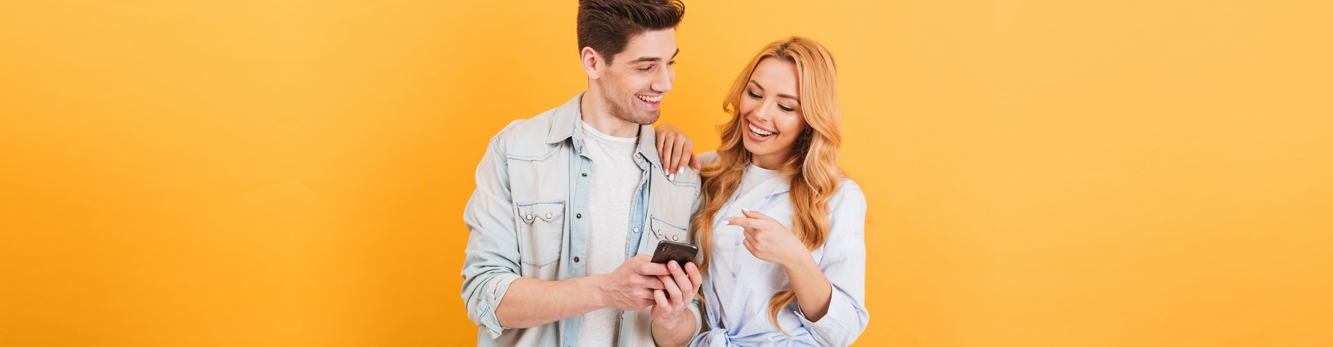 two people smiling while using their phone